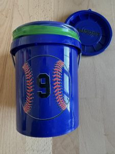 Tiny blue bucket from Lowe's with a sticker that has a baseball with the number nine in the middle.