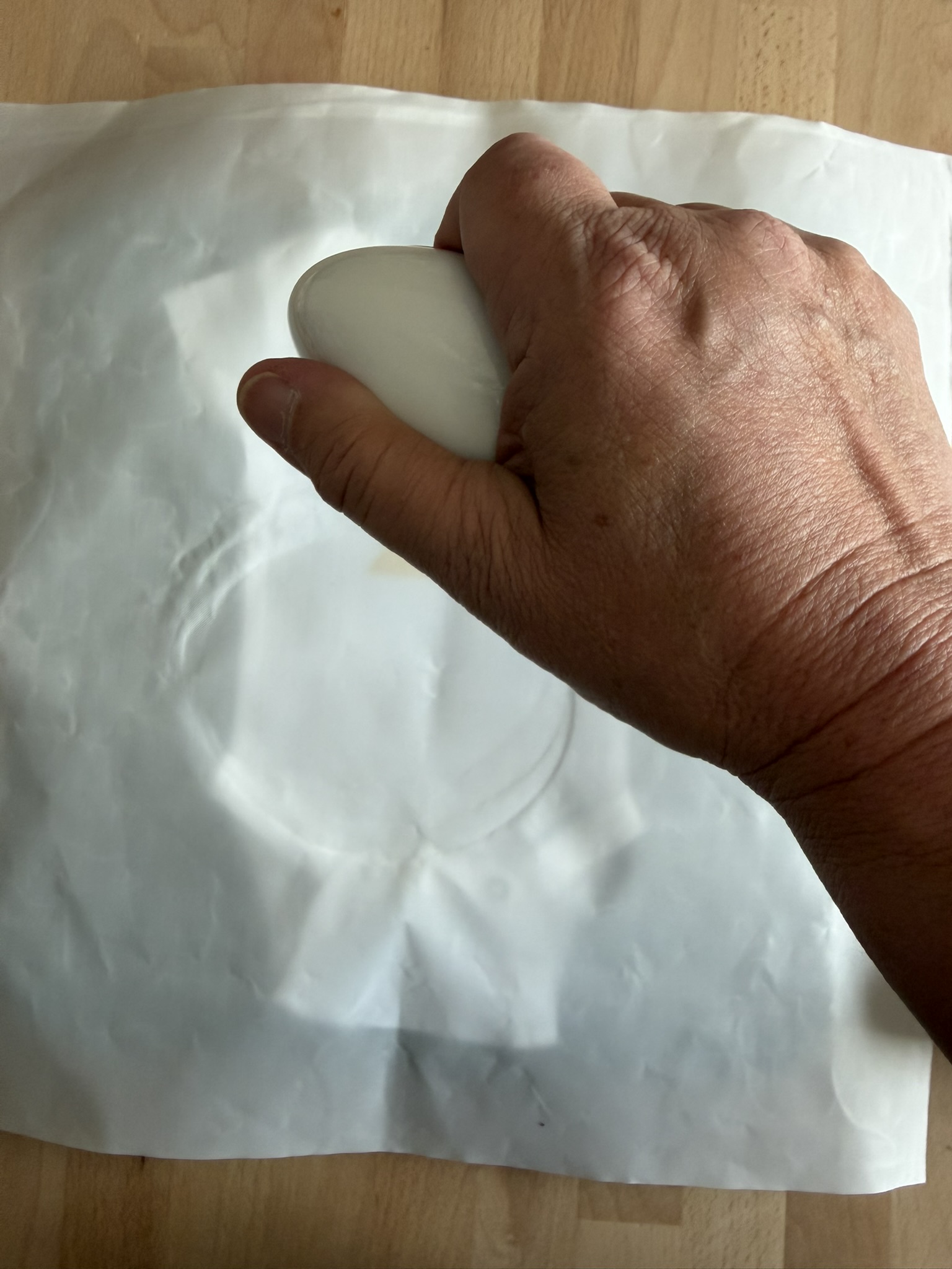 Woman's hand holding a Cricut mini press about to press a DTF design onto a preemie bodysuit to make a small Halloween costume.