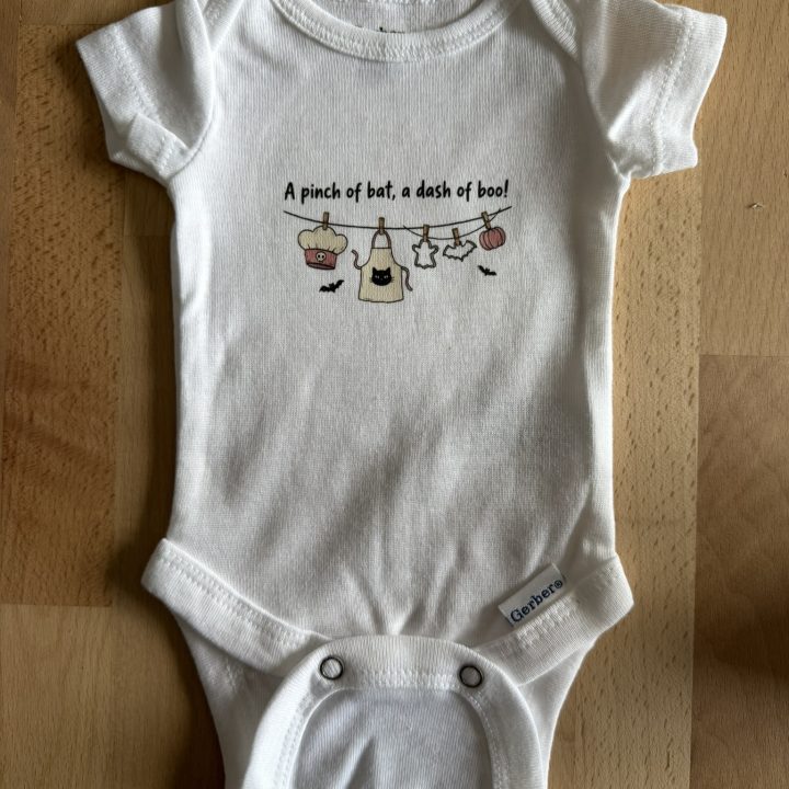 Preemie bodysuit on a wood table with a cute Halloween graphic as part of Preemies of the Carolinas Boo in the NICU.