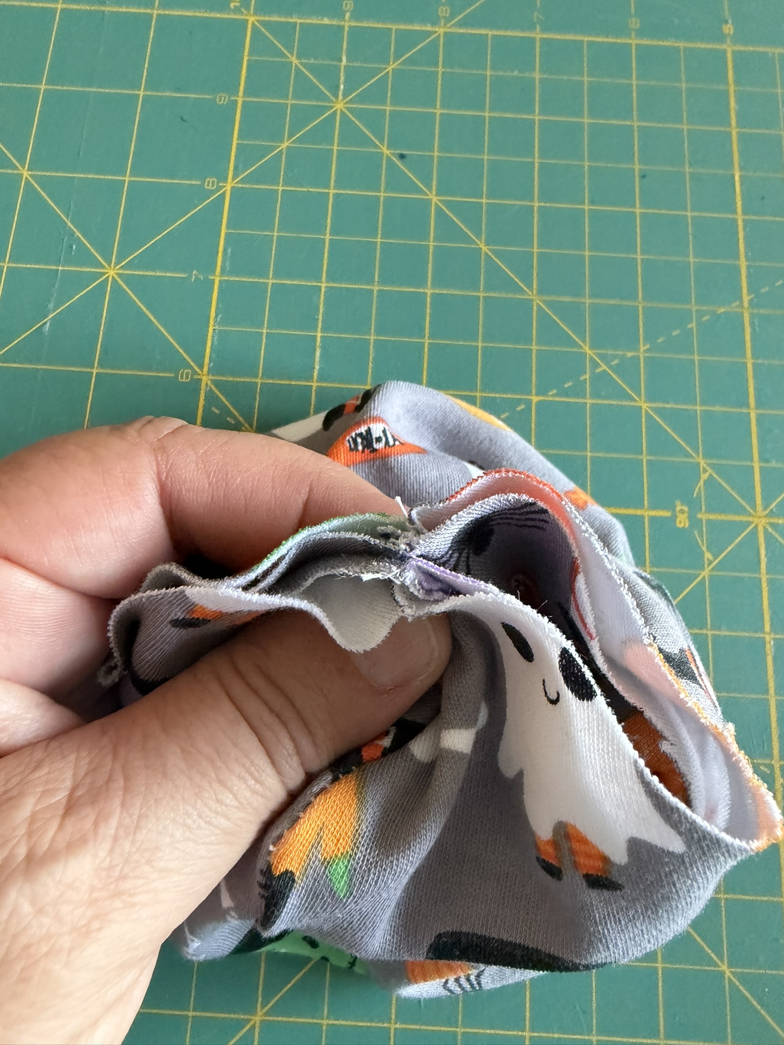 Center seams of the preemie beanie lined up for sewing held by a person's hand.