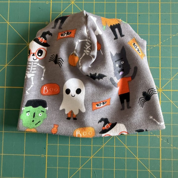 Finished preemie hat made in Halloween-themed knit fabric laid out on a green cutting mat.