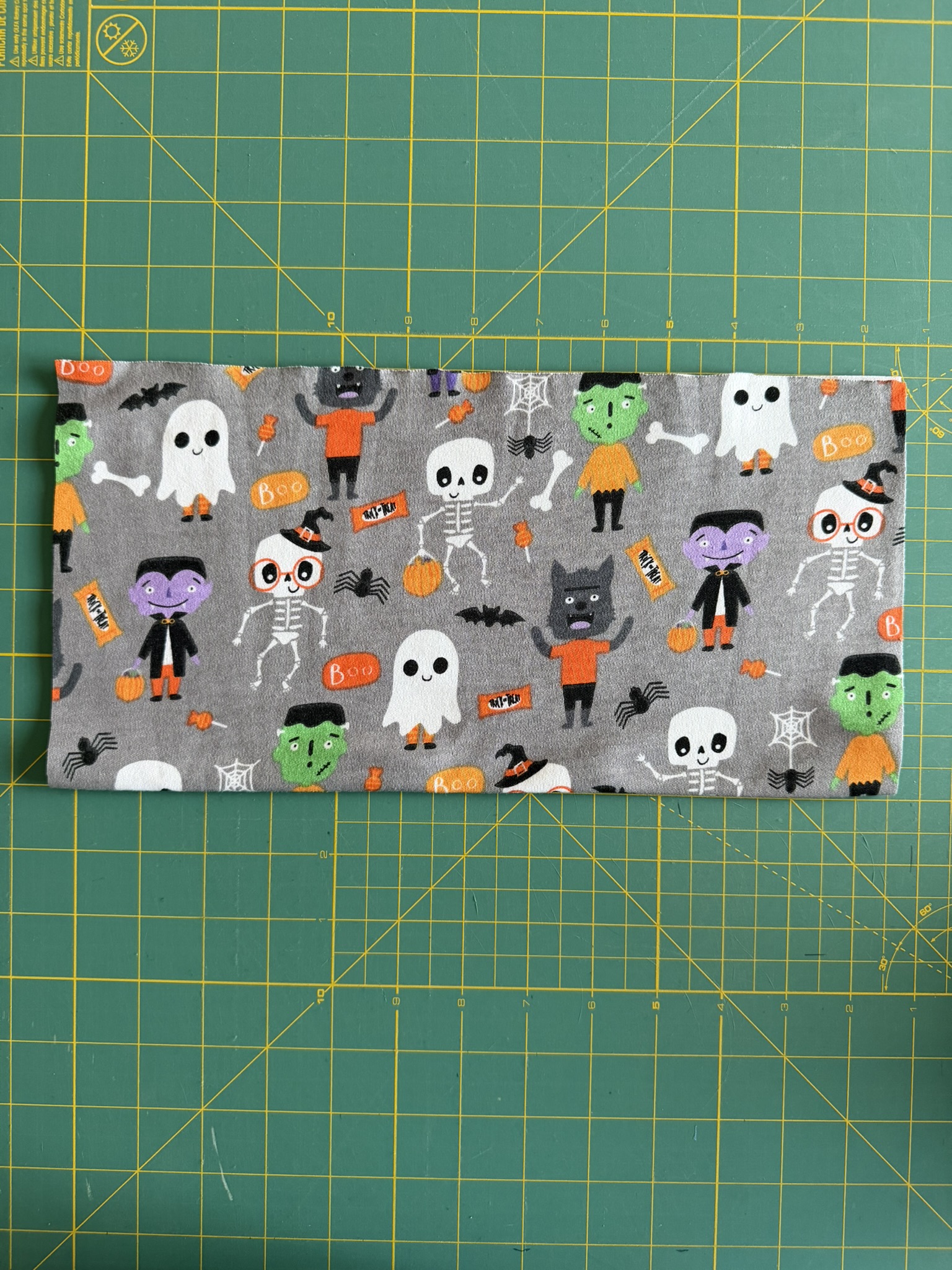 Halloween knit fabric folded and placed on a green cutting mat.