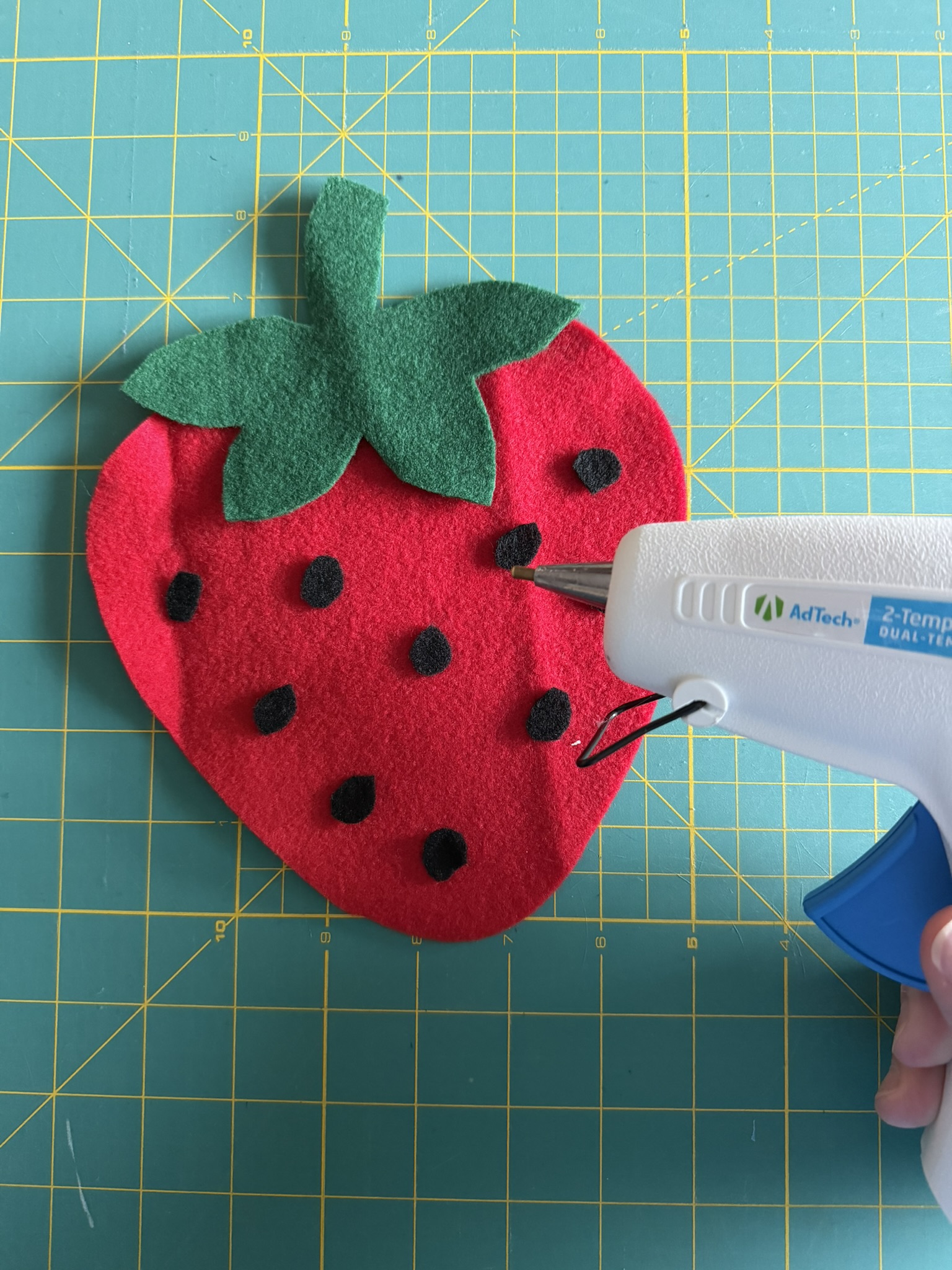 A felt strawberry and a white glue gun.