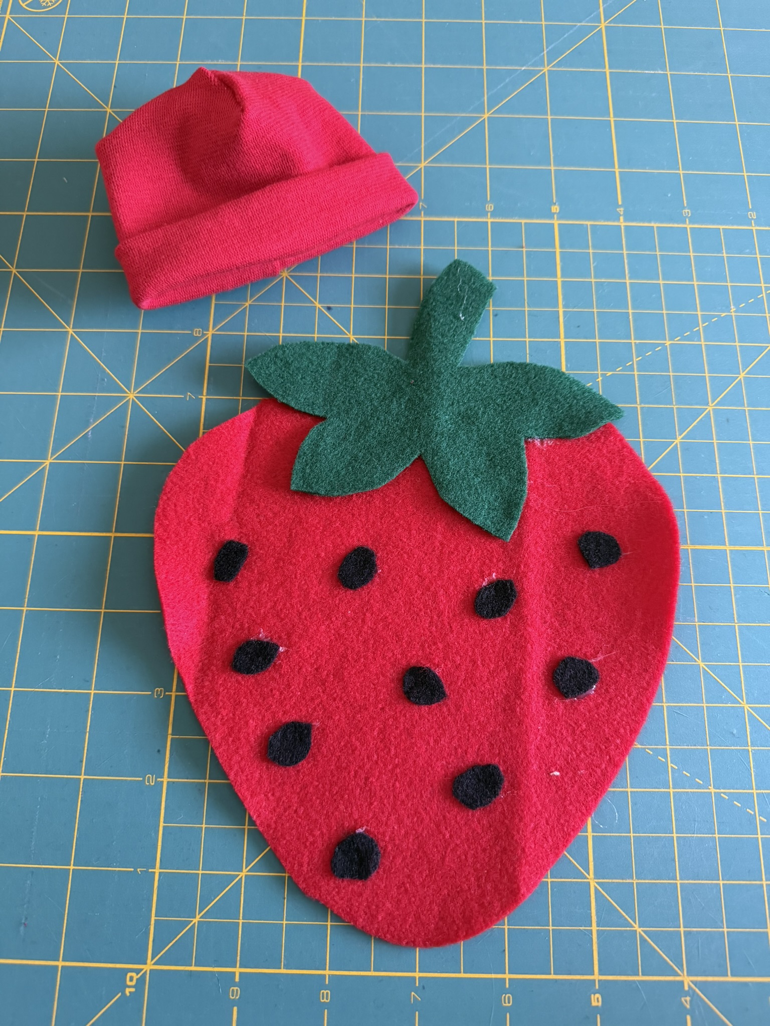 Handmade preemie Halloween costume made from felt that is a strawberry and matching red hat.