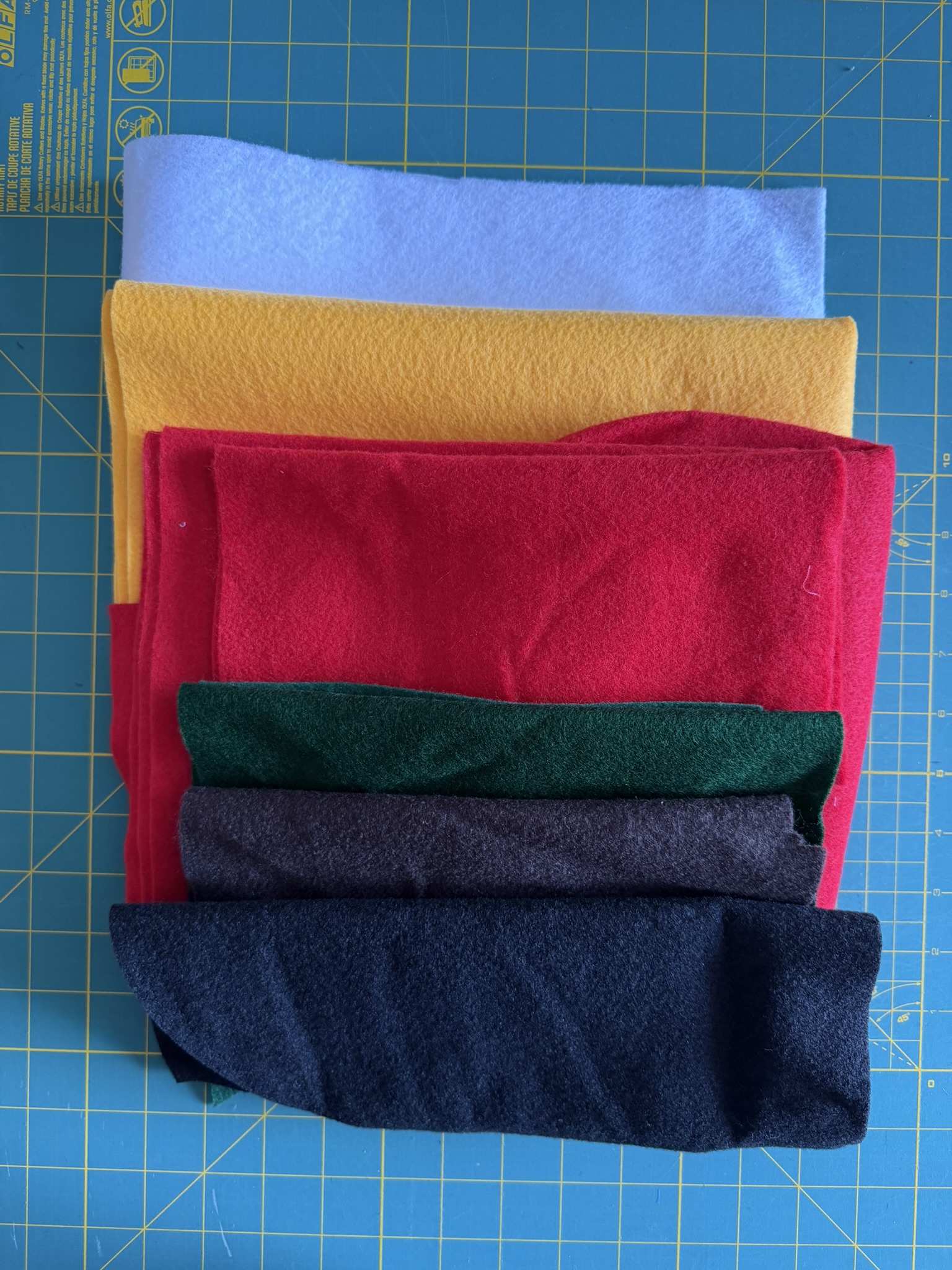 Felt fabric in a handful of colors laid out on a green cutting mat.