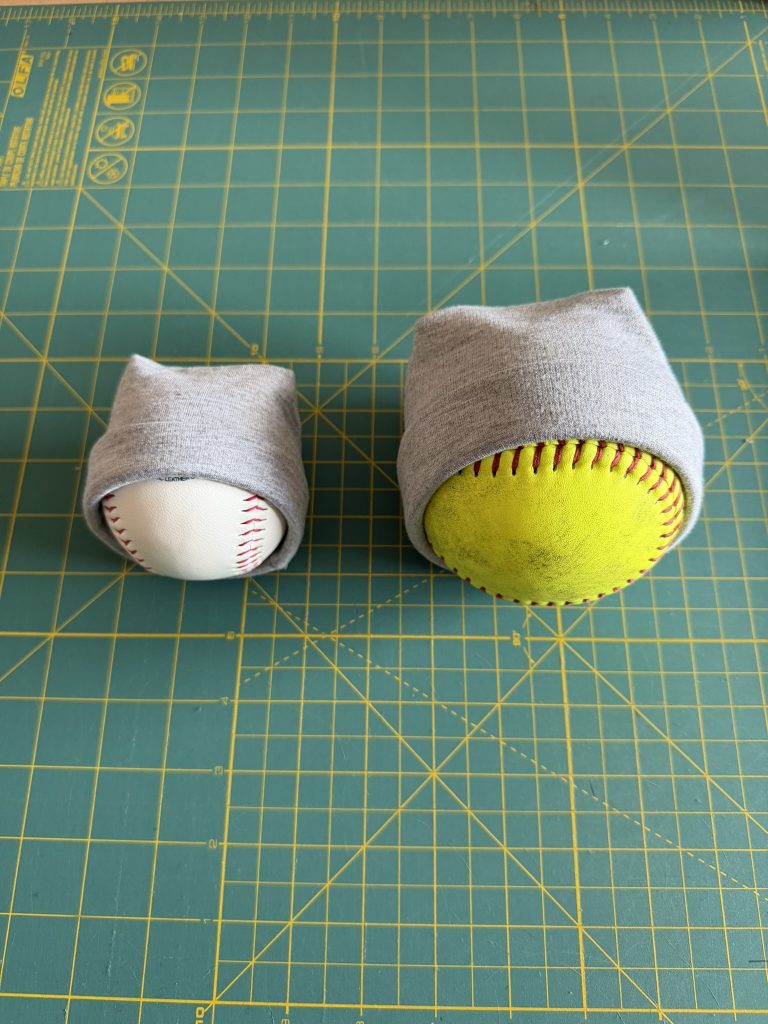 Preemie hats wrapped over a baseball and softball to show appropriate hat sizing for premature babies.
