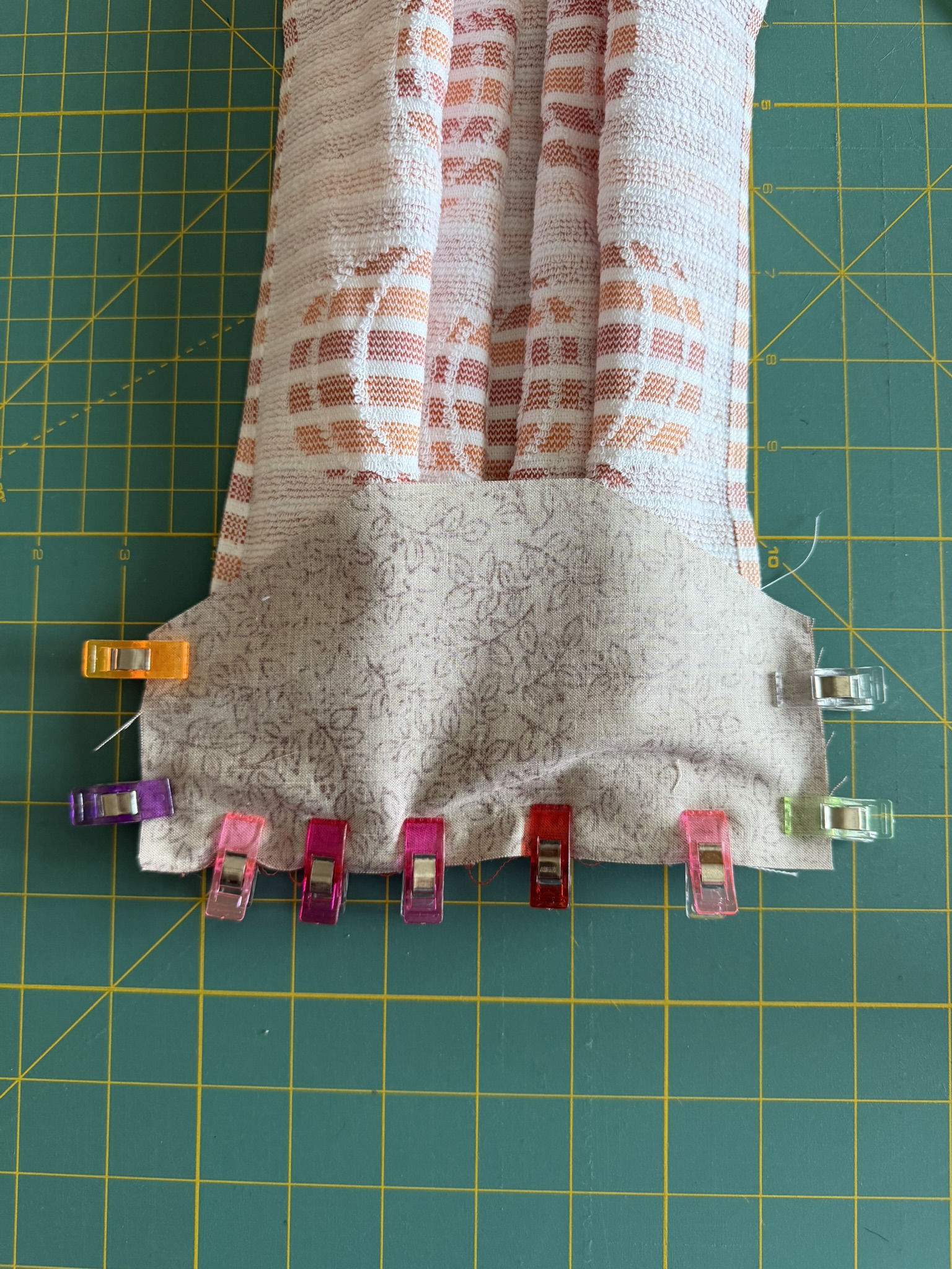 Sewing clips placed around fabric that is the top of a hanging dish towel.