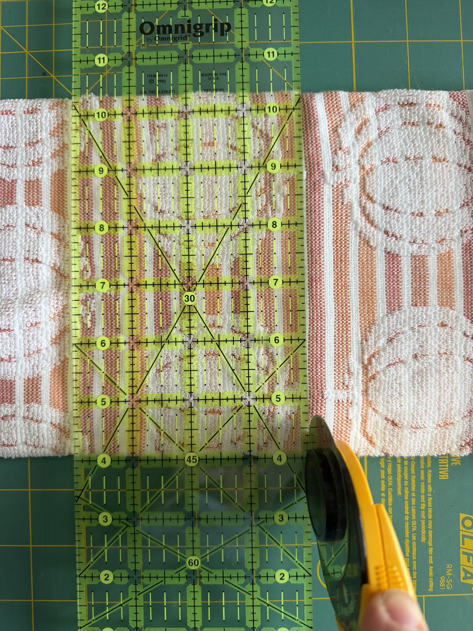 Hand towel with pumpkins that has a ruler and rotary cutter on top of it.