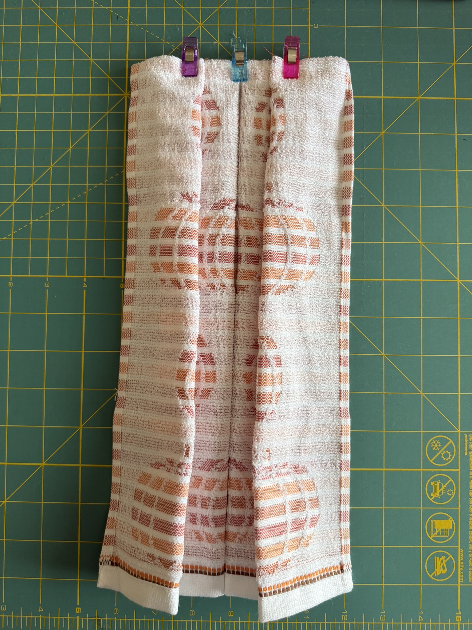 Pumpkin towel folded and clipped to prepare for sewing.
