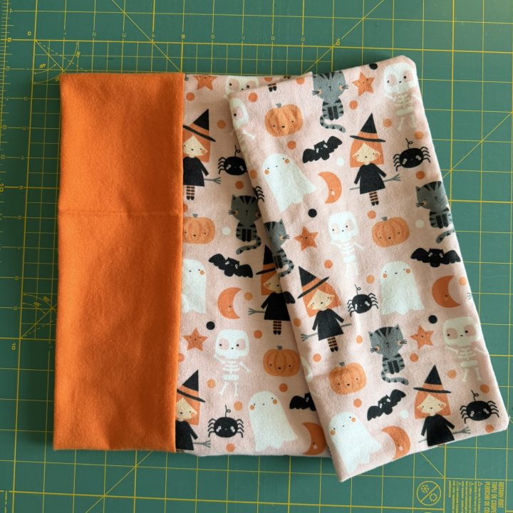 Toddler pillowcase made from flannel fabrics with an orange border and a cute Halloween-themed print containing ghosts, witches, and skeletons.
