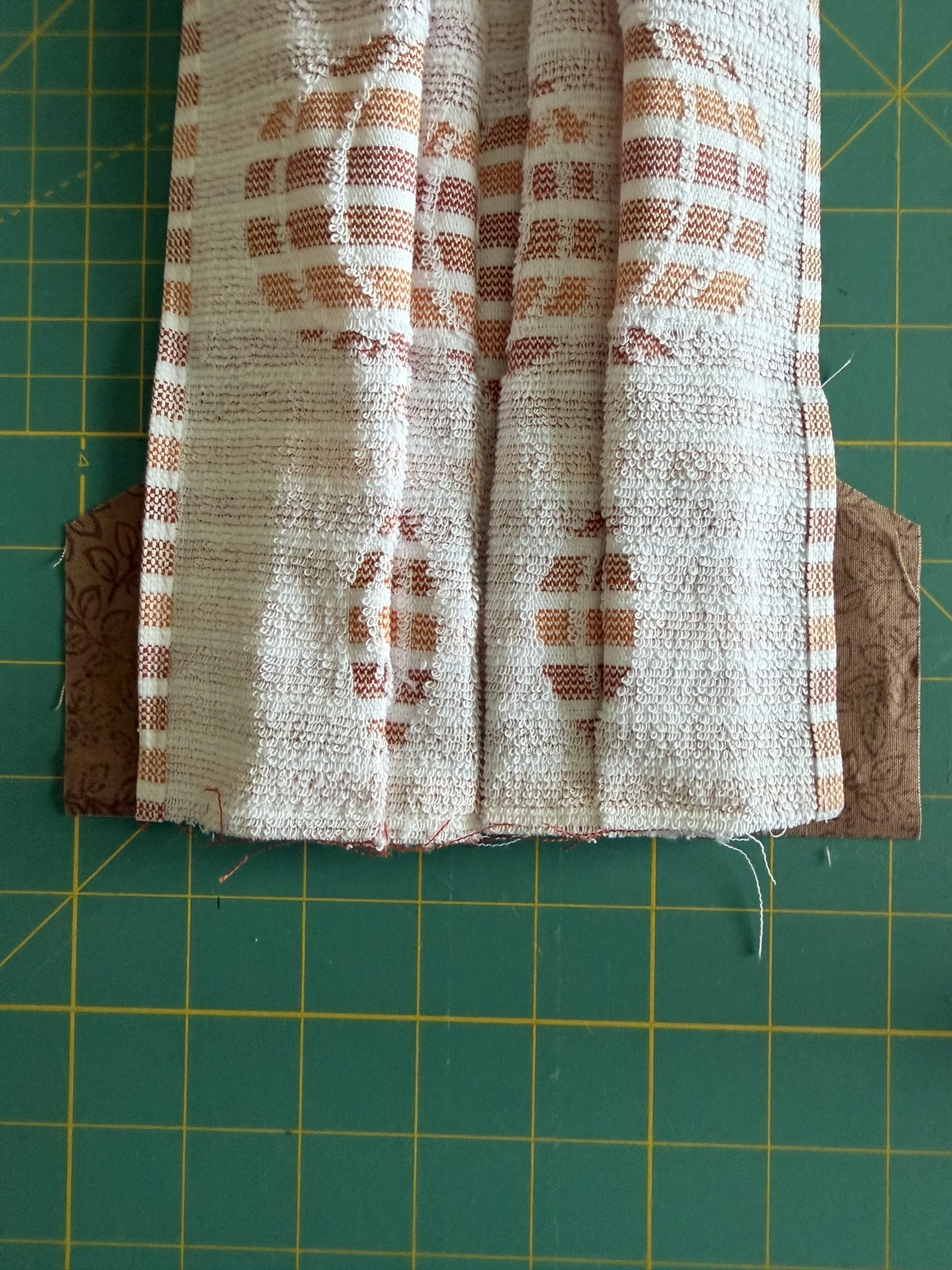 Towel placed on top of brown fabric as part of the hanging towel tutorial.